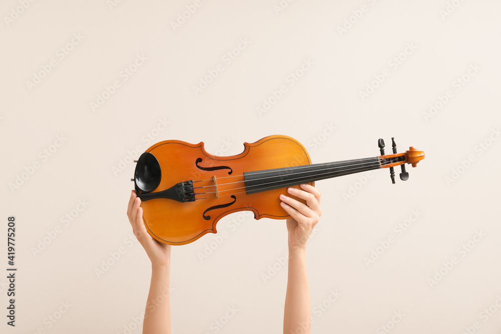 Woman holding violin on color background