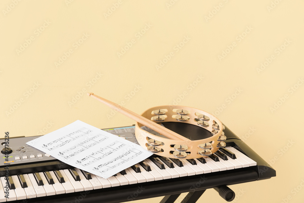 Synthesizer, tambourine, drumsticks and music notes on color background