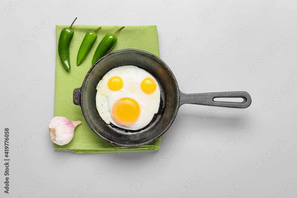 Frying pan with tasty eggs on light background