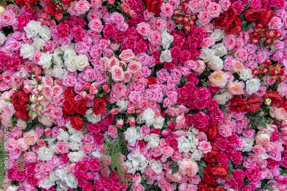 Background of artificial roses of different colors, pink reds white roses