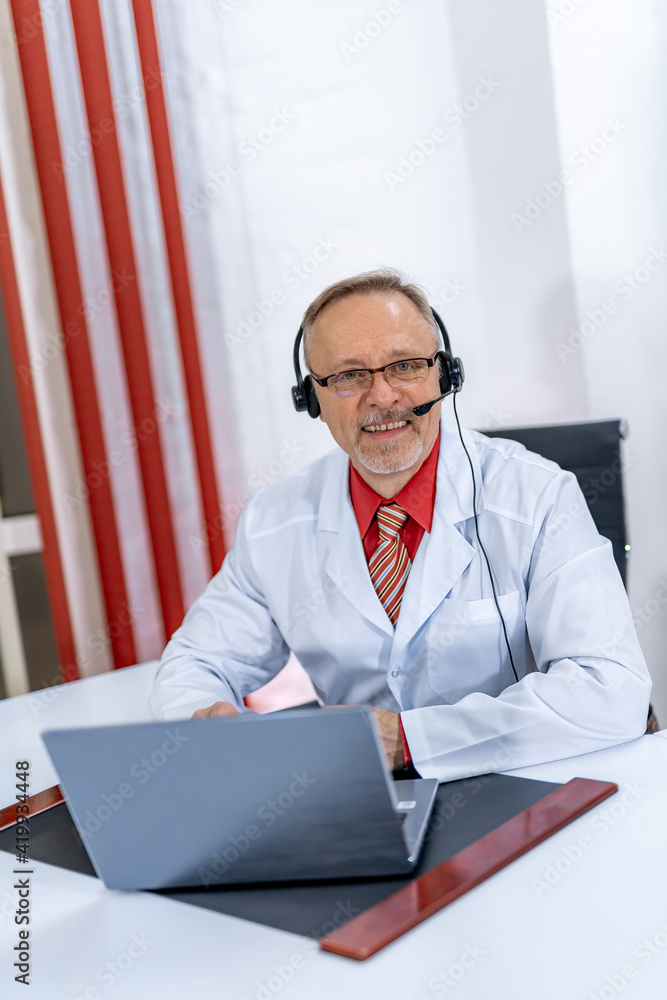 Smiling doctor gives online consultation in modern clinic. Professional medic speaks via headphones 