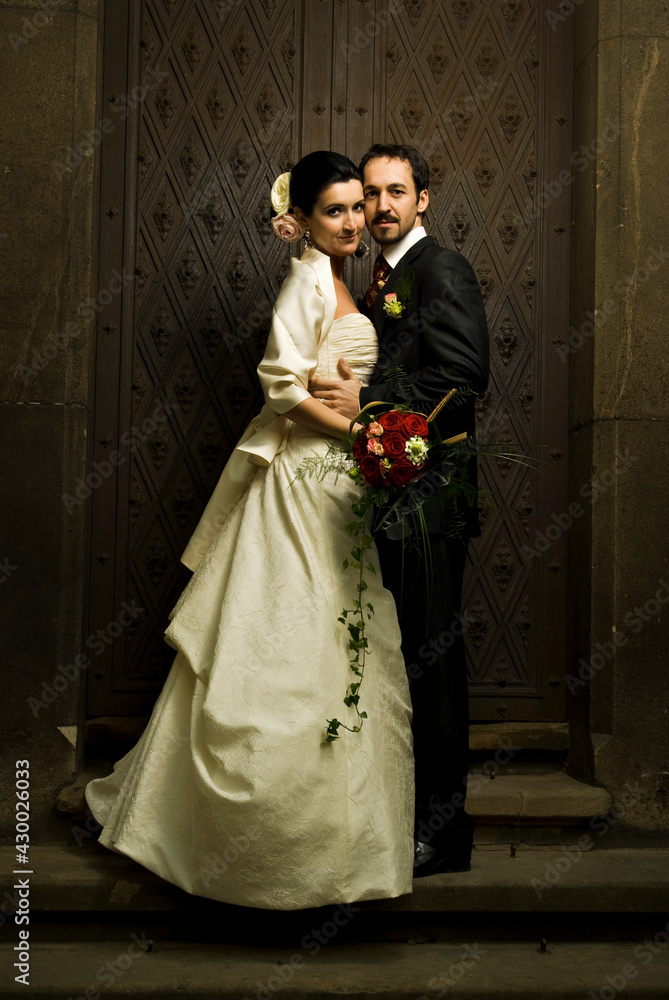 Gorgeous wedding couple (bride and groom) standing on staircase in front of historical church doorwa