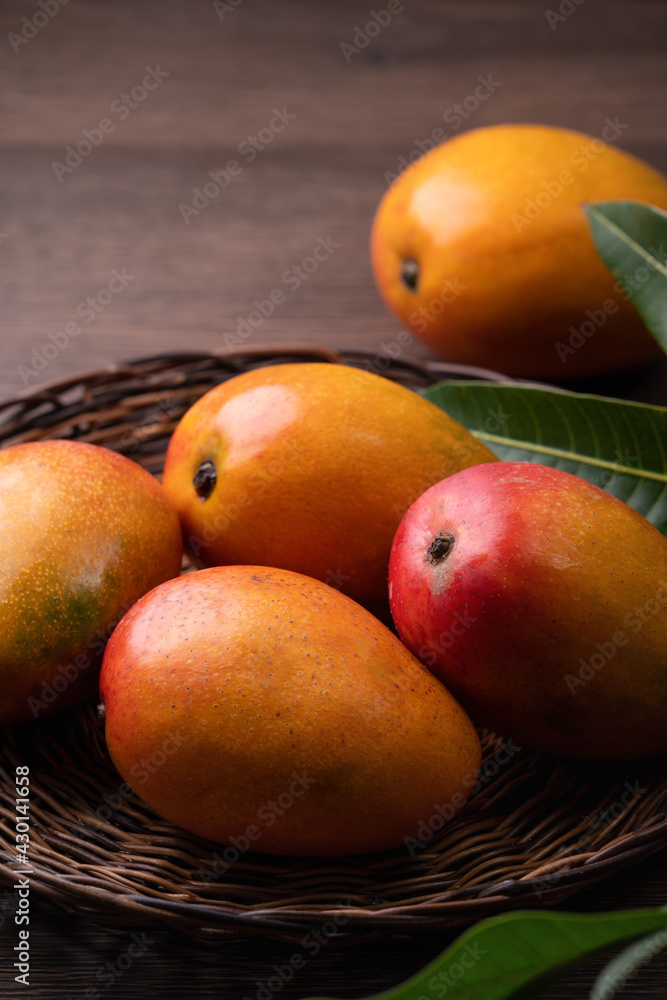 Mango. Fresh mango fruit on a bamboo sieve over dark wooden table background.