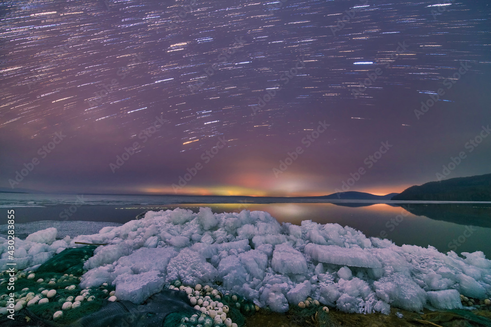 The milky way and star trails in sky, ice and snow.