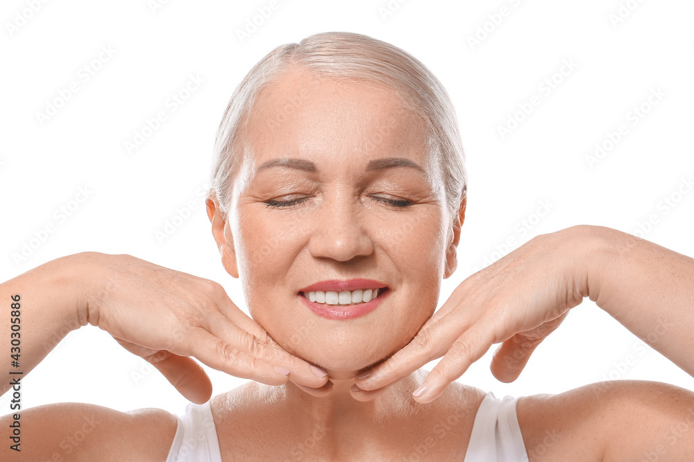 Mature woman giving herself face massage on white background