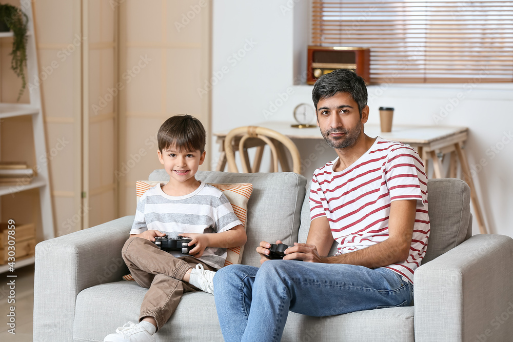 Father and little son playing video games at home