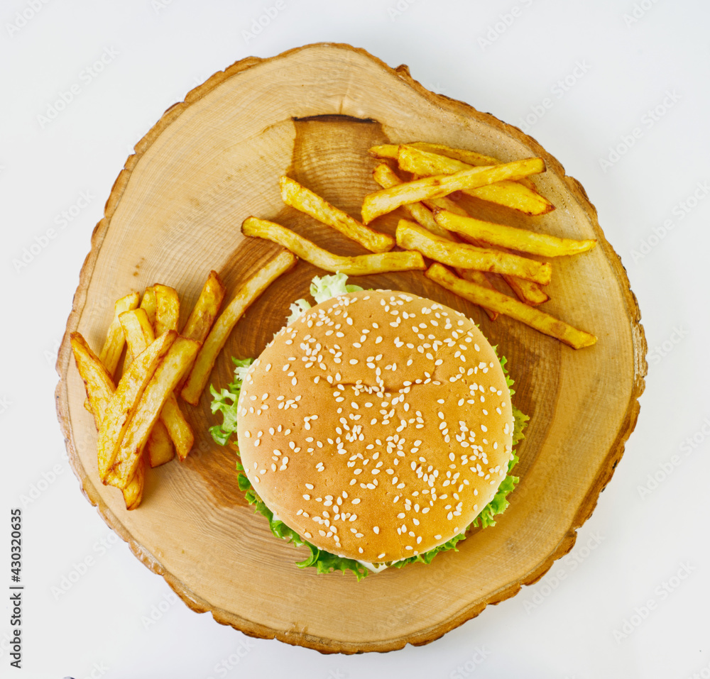 Hamburger and french fries on stump cutting board, top view