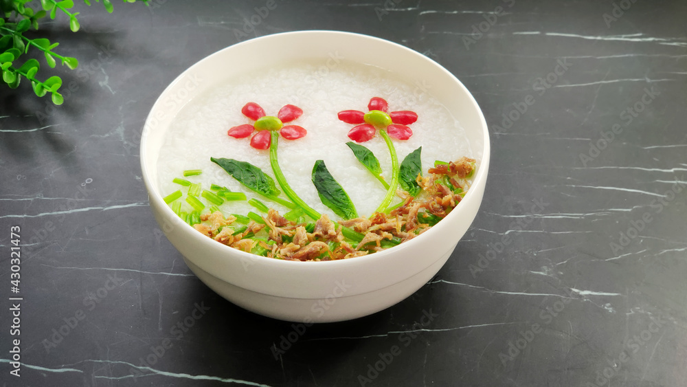 Flower pattern on white rice porridge with cherry tomatoes, spinach and shredded pork, black marble 