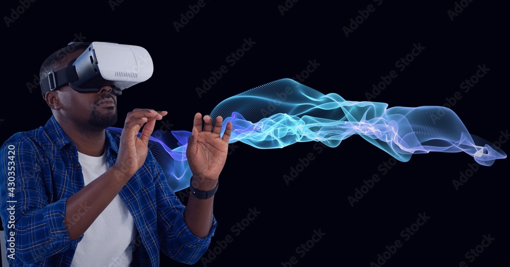 Composition of man wearing vr headset touching screen over blue light trails on black