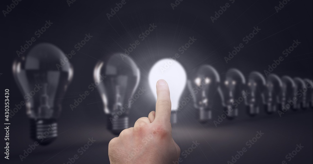 Composition of finger touching lit light bulb with row of light bulbs on black background