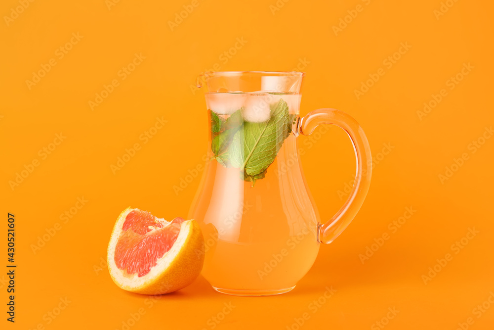 Jug of tasty grapefruit lemonade on color background