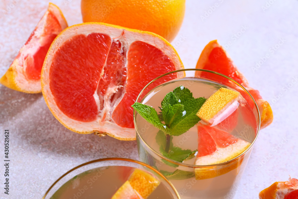 Glasses of tasty grapefruit lemonade on light background