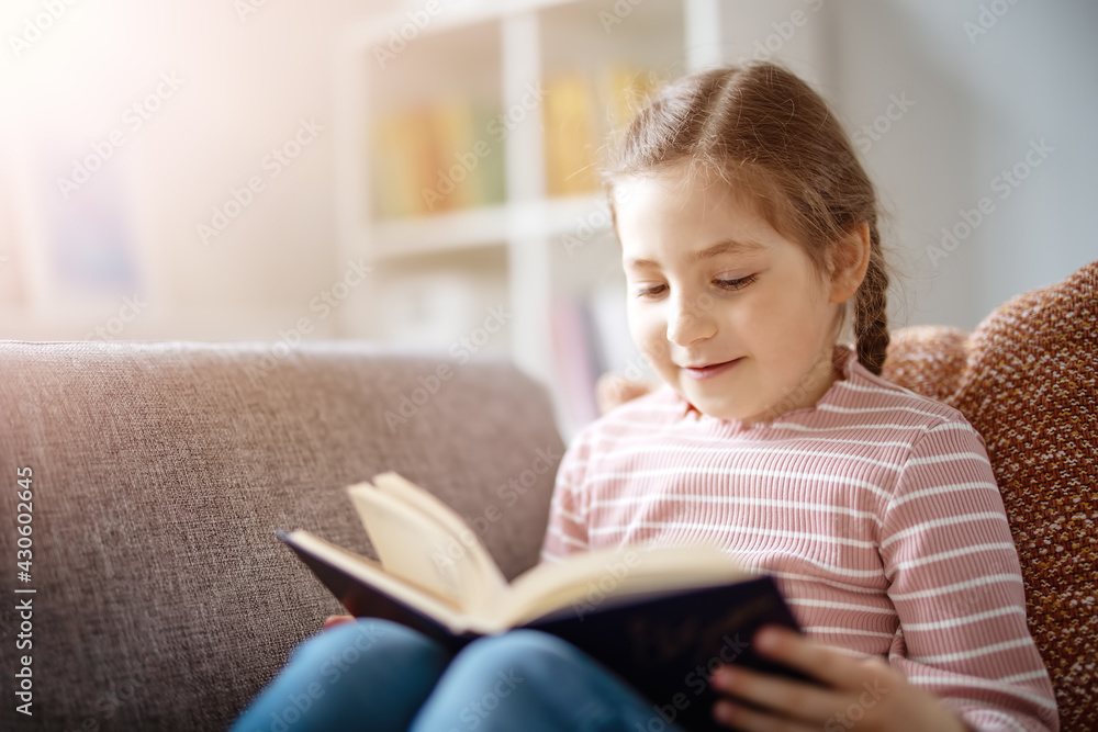 Pretty girl have a rest on the cozy couch with interesting book