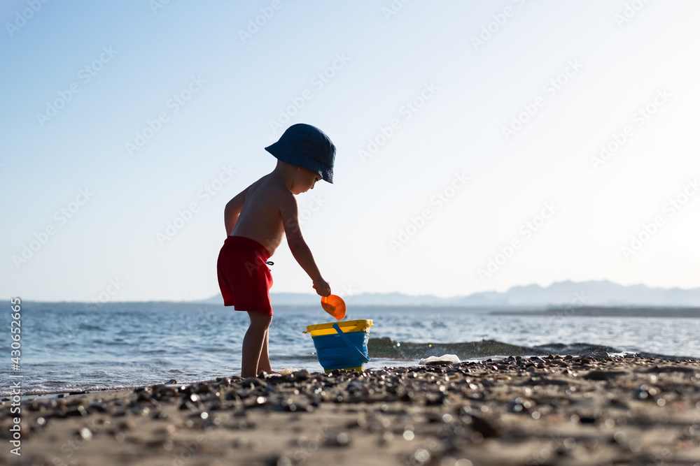 Boy kid in red shorts on the summer beach