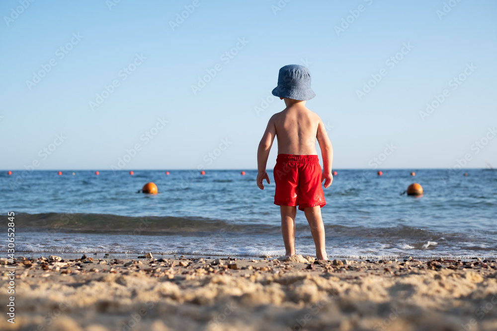 夏日海滩上穿着红色短裤的男孩