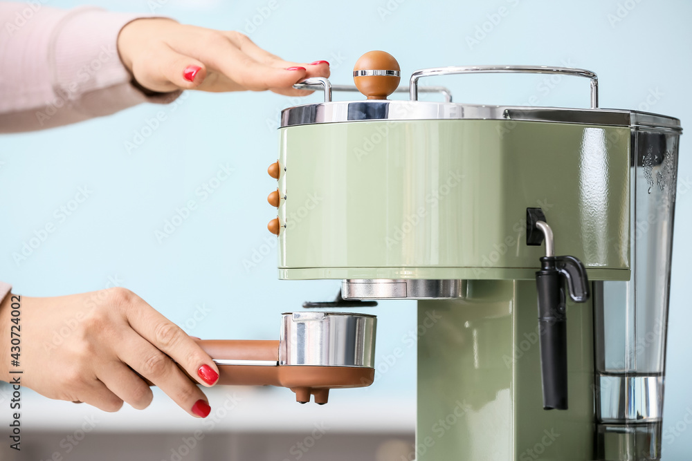 Woman making coffee with machine in kitchen, closeup