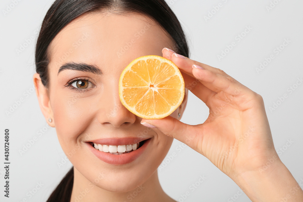 Beautiful young woman with lemon on light background