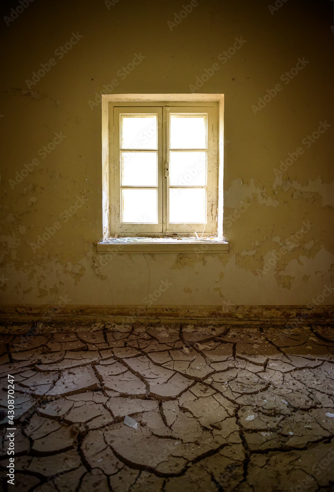 Room interior in abandoned house, vertical shot. Cracked dry clay on the floor, peeling yellow paint