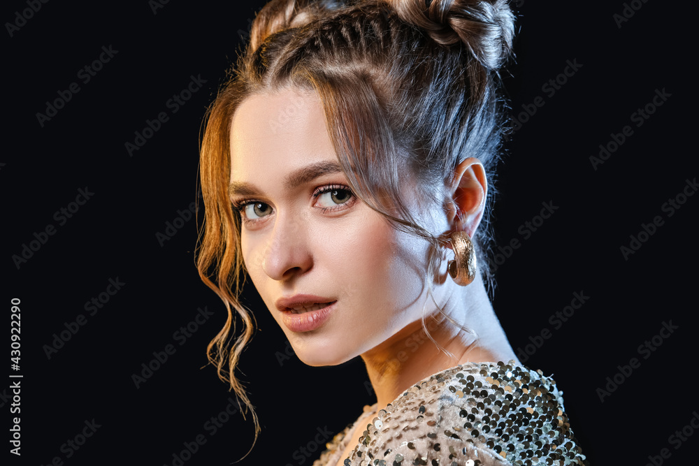 Beautiful young woman with braided hair on dark background