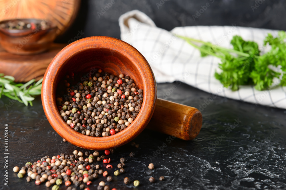 Mortar and pestle with peppercorns on dark background