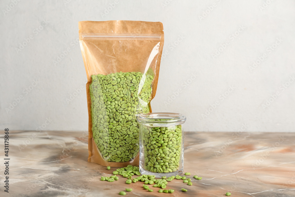 Jar and bag with green coffee beans on light background