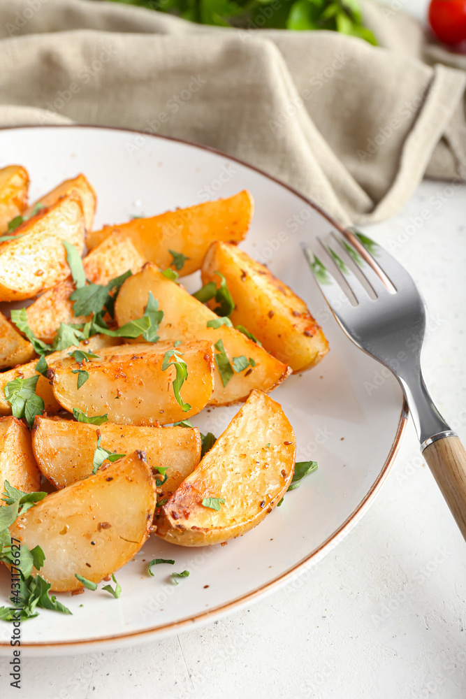 Plate of tasty fried potatoes with parsley on light background