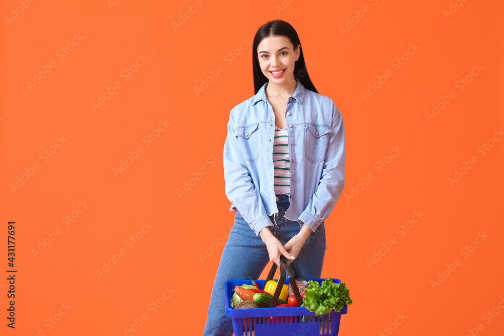 Young woman with shopping basket on color background