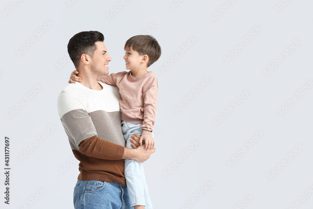 Happy father and his little son on light background