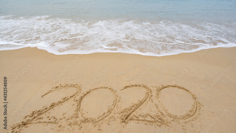 2020 Text on the beach, 2020 year message hand written in sand on beautiful beach Waves crashing on 