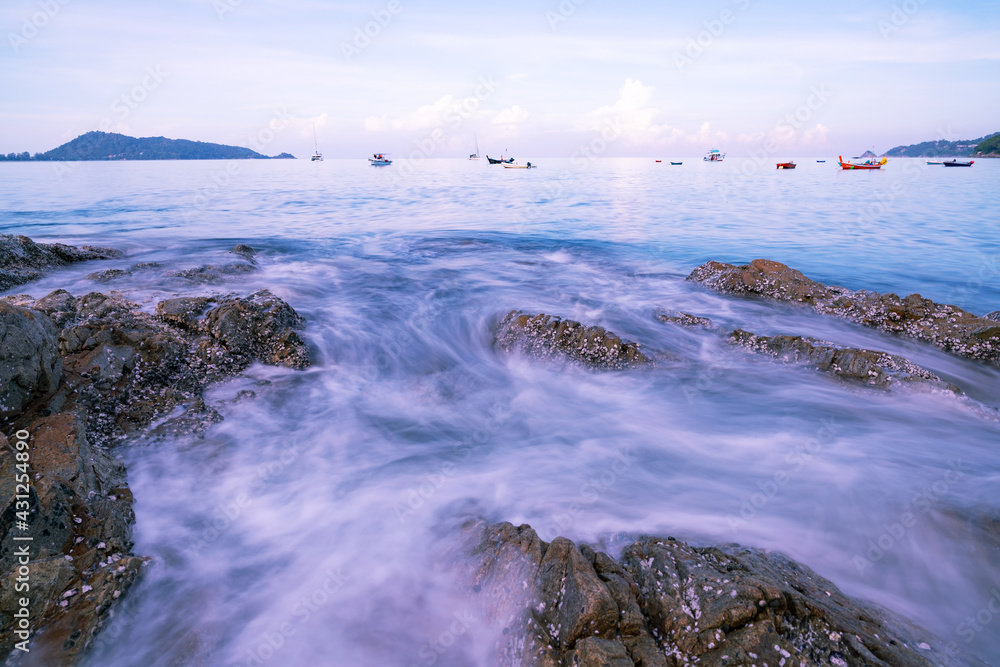 美丽的长时间暴露海景与海浪在海边的岩石上形成密集的白色泡沫