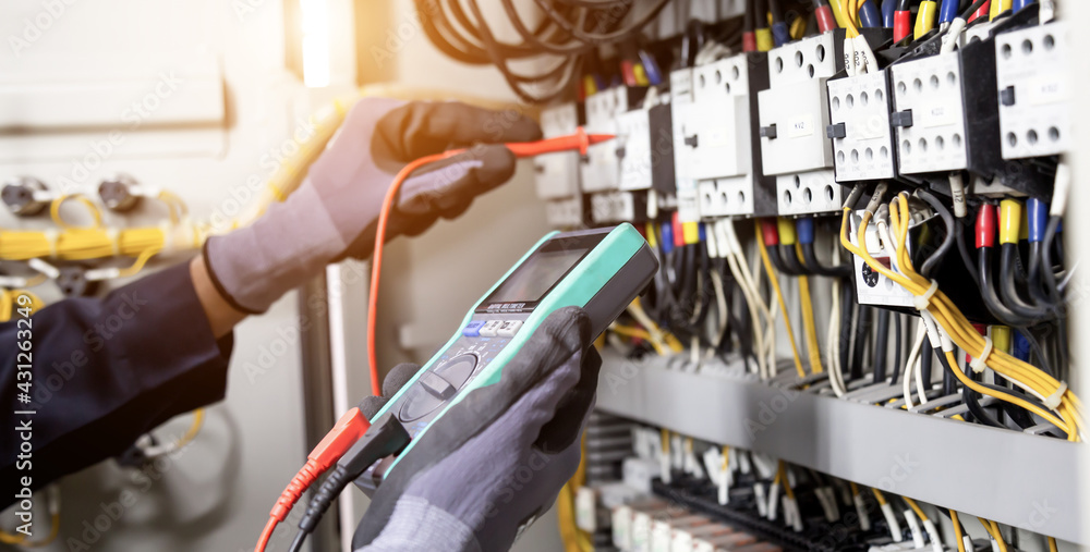 Electrician engineer tests electrical installations and wires on relay protection system. Adjustment