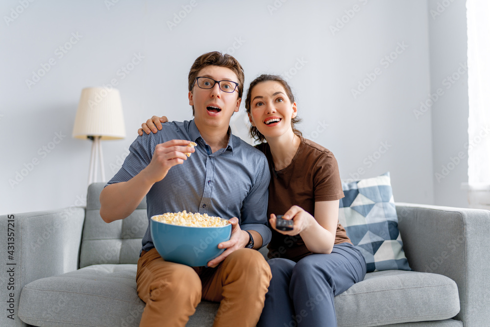 couple with popcorn sitting on sofa