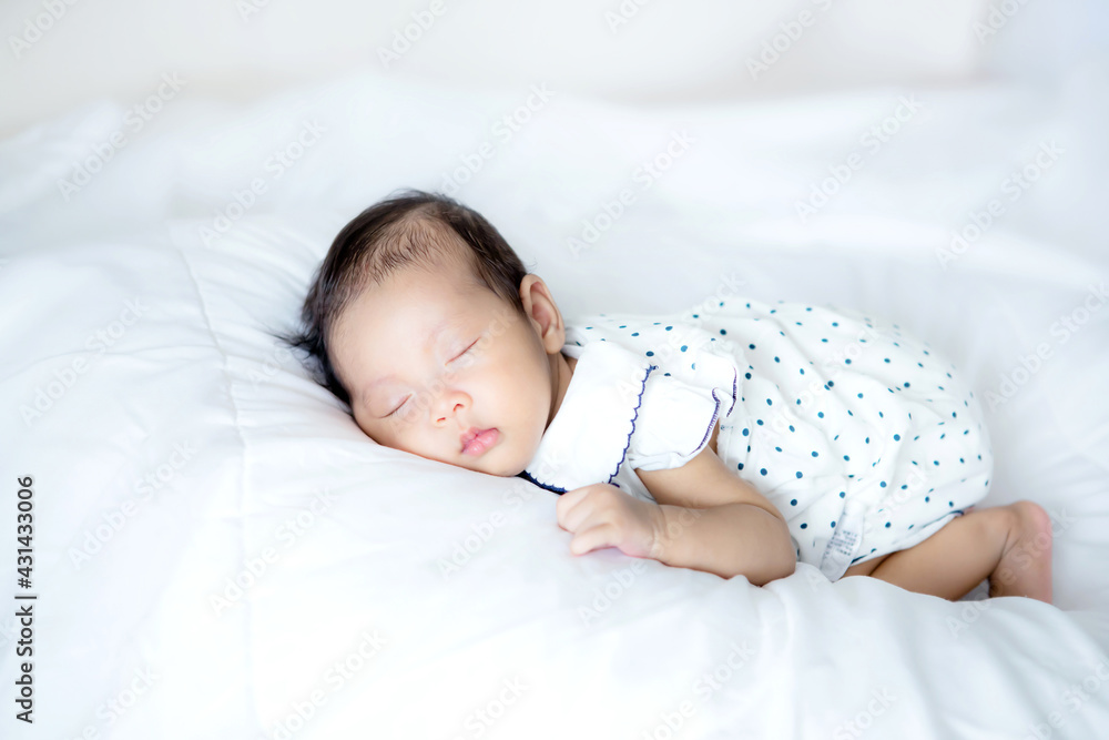 Close up adorable asian 3 months years old baby girl sleeping on a white bed , newborn peace sleepin