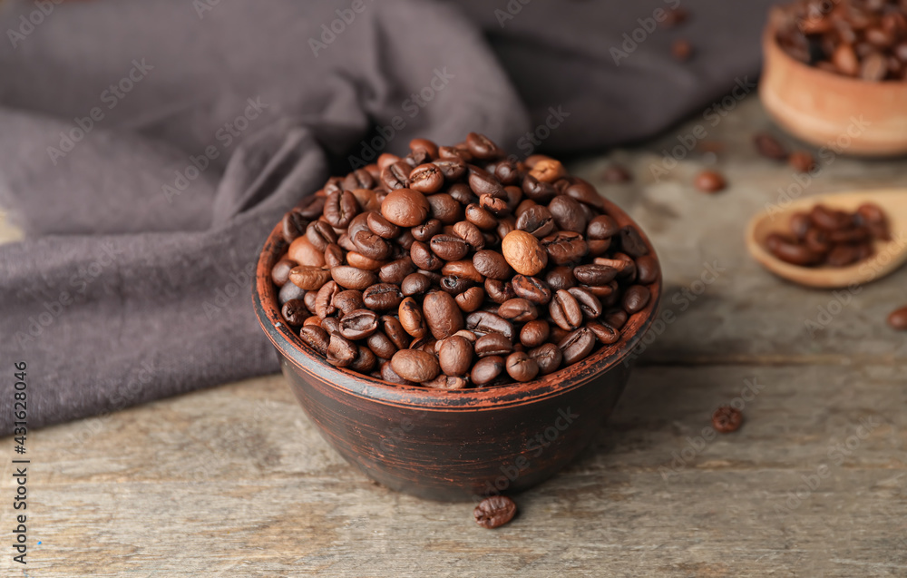 Bowl with coffee beans on wooden background