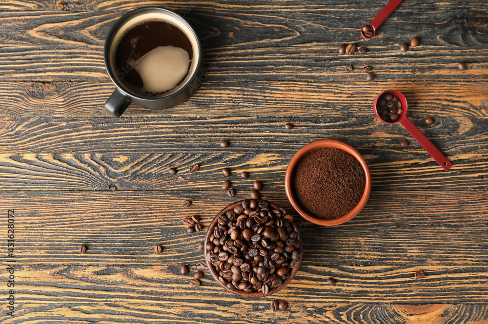 Cup of coffee, bowls with beans and powder on wooden background