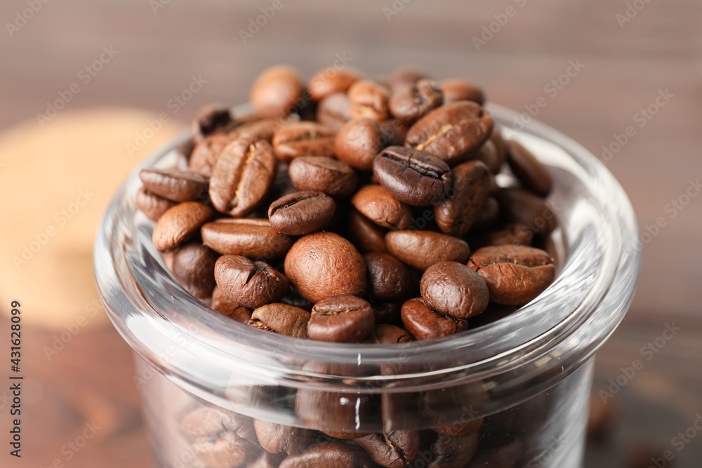 Jar with coffee beans on wooden background