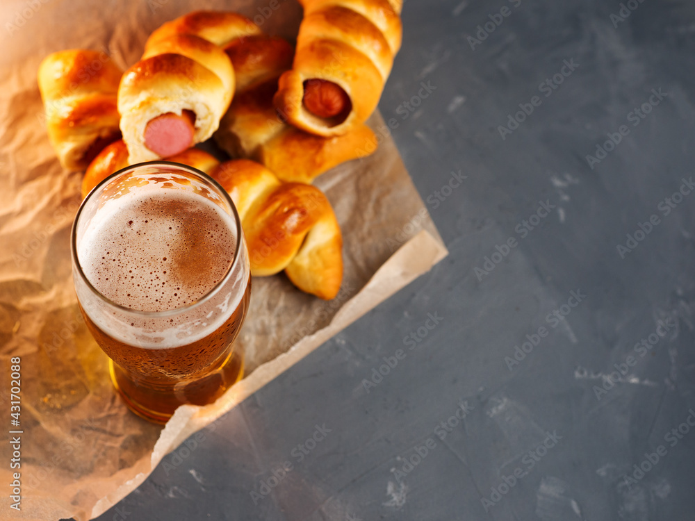 A glass of light beer and sausages, top view on a gray table and copy space