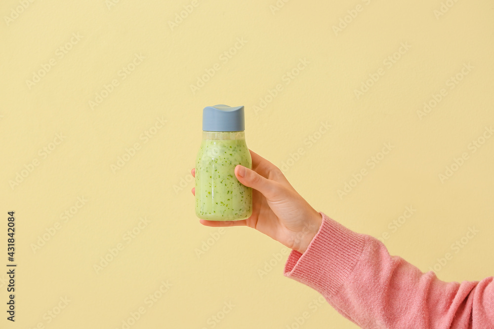 Woman with bottle of fruit smoothie on color background