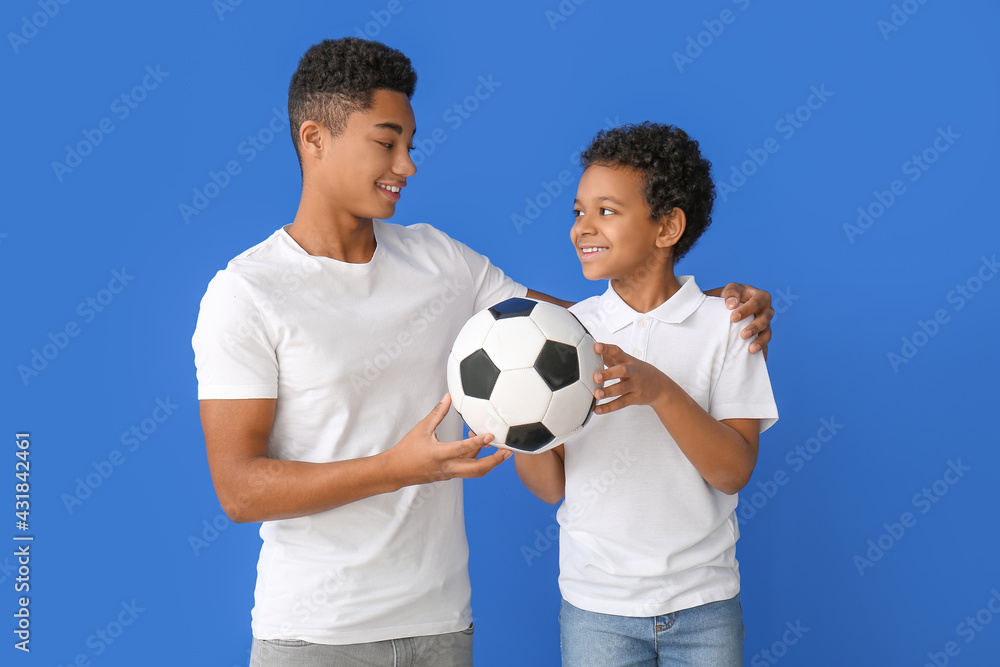 African-American boys with ball on color background