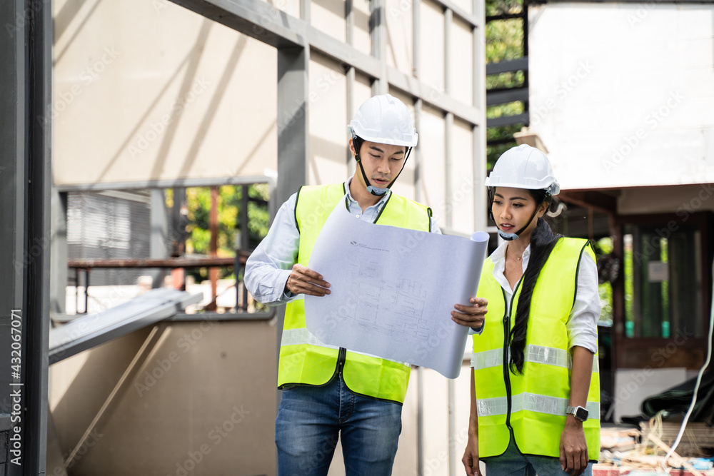 Asian young male and female engineer look at drawing and discuss.