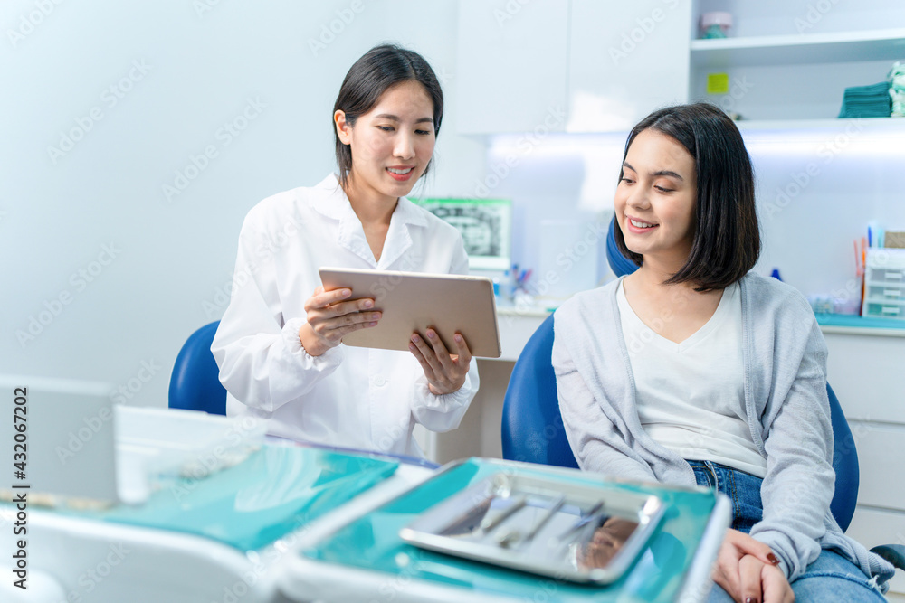 Asian female dentist using tablet to present oral treatment program.