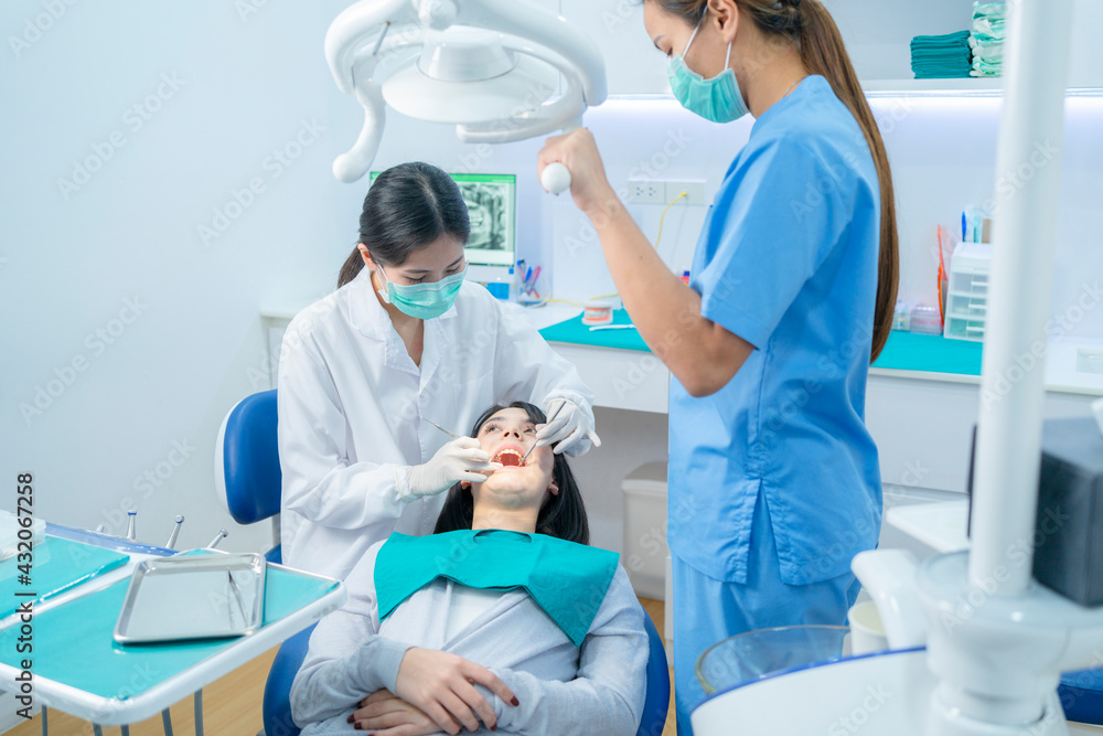 Asian dental team providing oral treatment to patient in dental clinic