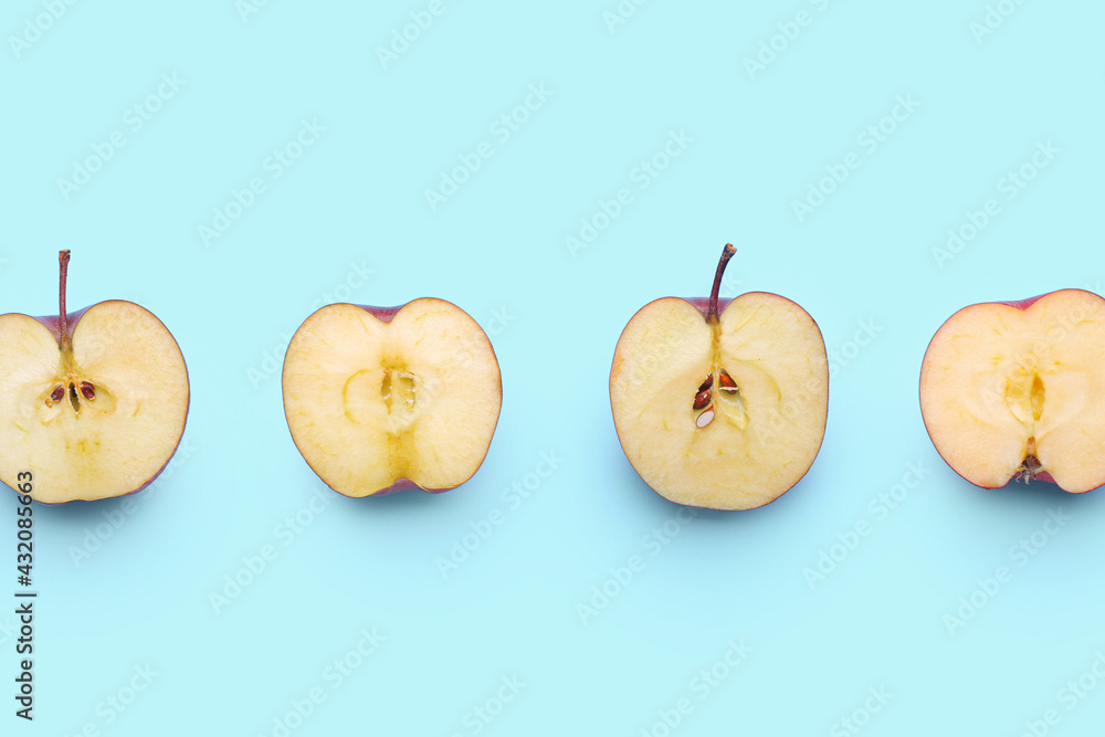 Pieces of fresh red apples on color background