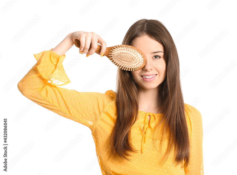 Beautiful young woman with hair brush on white background