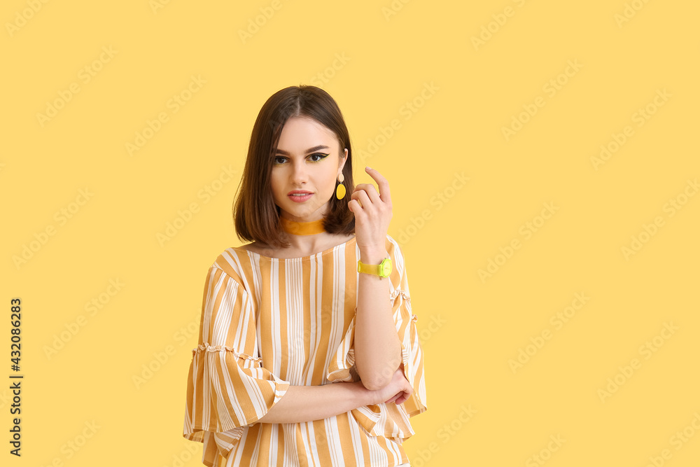 Stylish young woman on yellow background