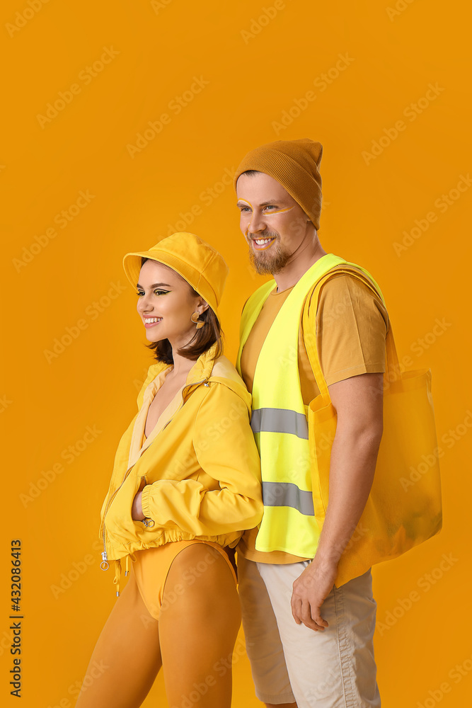 Stylish young couple on yellow background