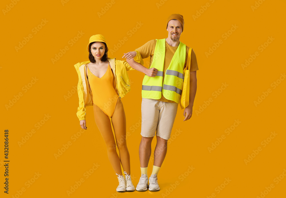 Stylish young couple on yellow background