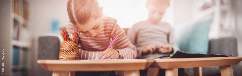 Children playing together with modeling clay and drawing by pencils.