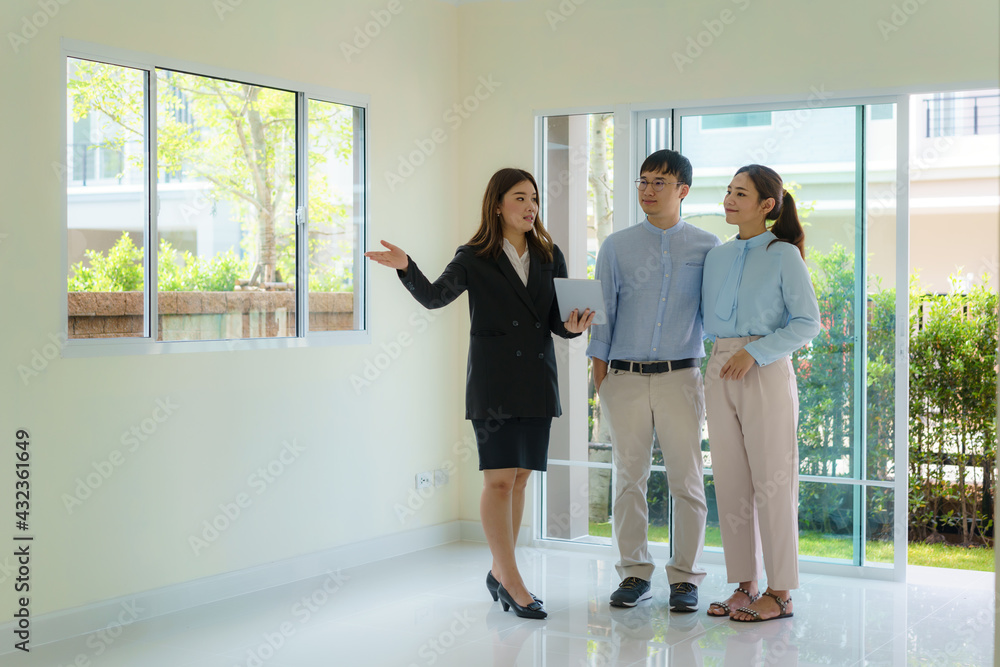 Asian woman Real estate broker agent showing a house detail in her digital tablet to the young Asian