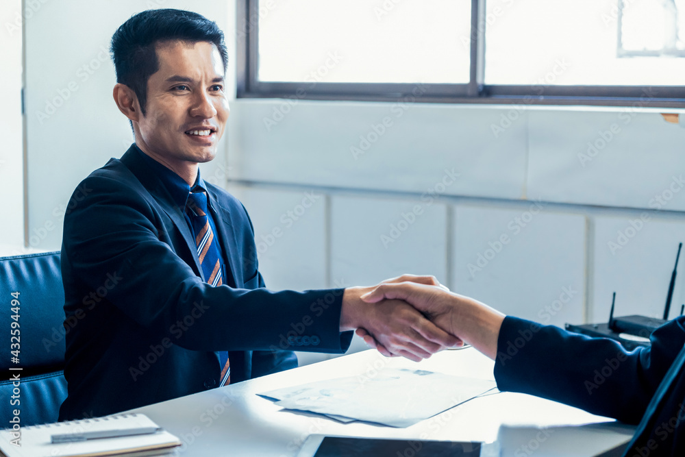 Business people agreement concept. Businessman and Asian businesswoman do handshake in the office.